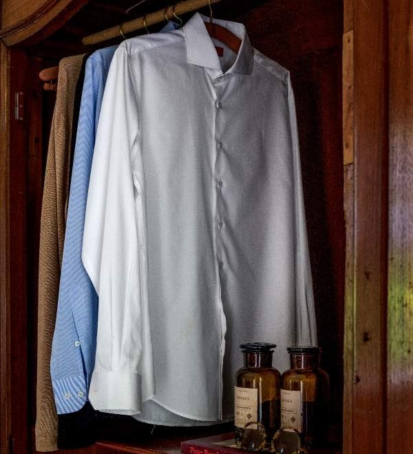 Camisas sociais claras penduradas dentro de um armário