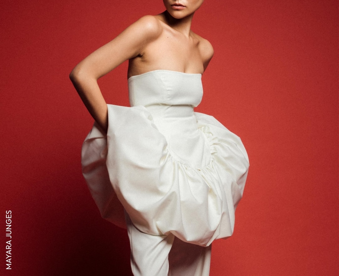 Modelo com vestido branco volumoso em fundo vermelho